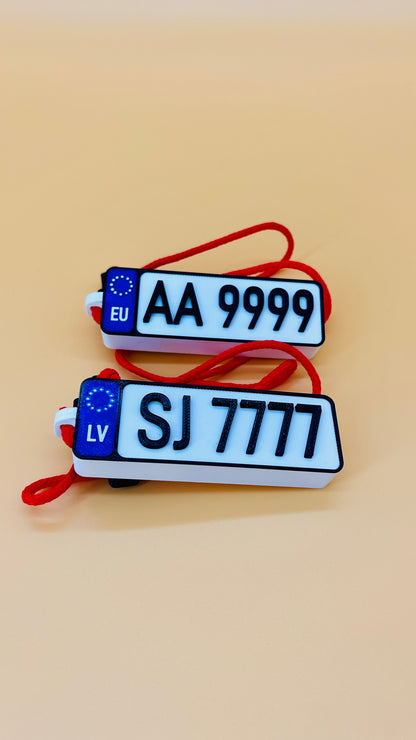 Two license plate-shaped keychains with text on a beige background