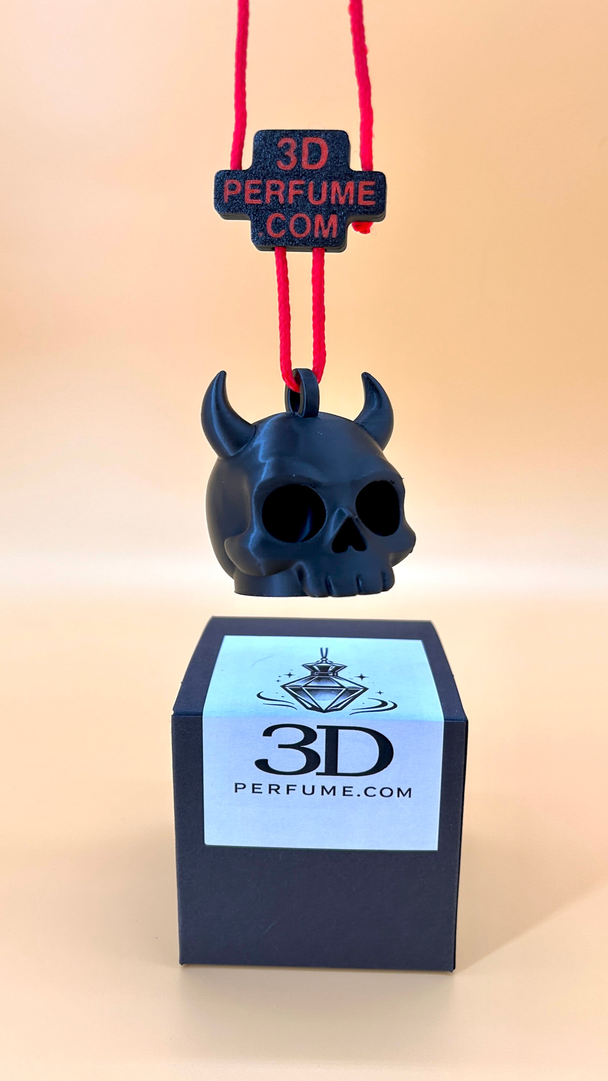 Black skull-shaped 3D perfume bottle with red string and '3D Perfume.com' label on a beige background.