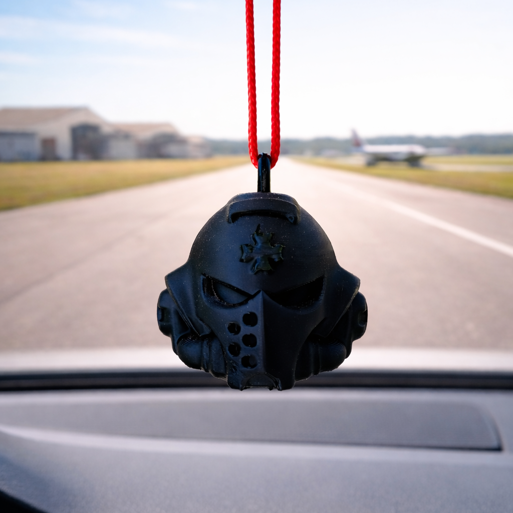 Black car air freshener shaped like a skull hanging from a red string inside a car.