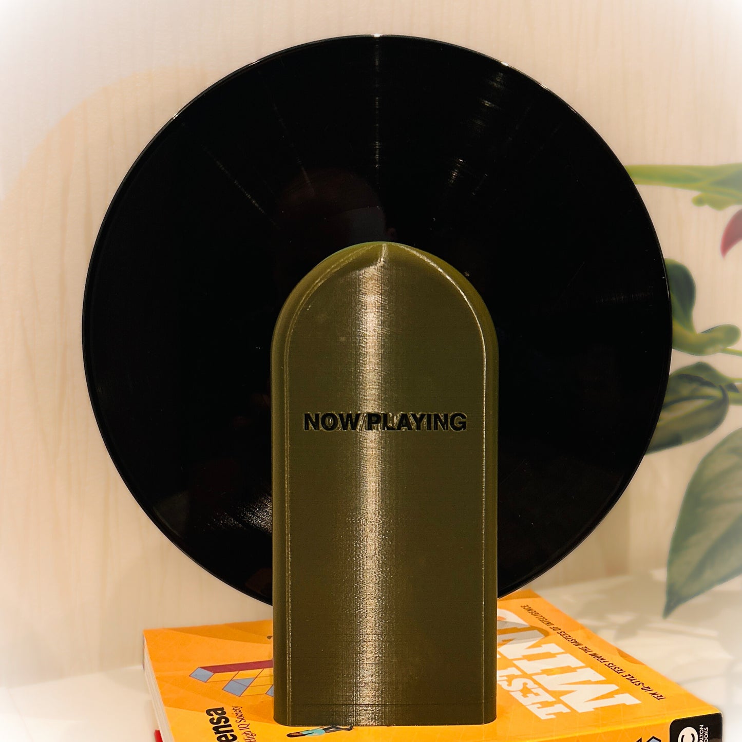 Vinyl record with a gold 'NOW PLAYING' needle on a white surface